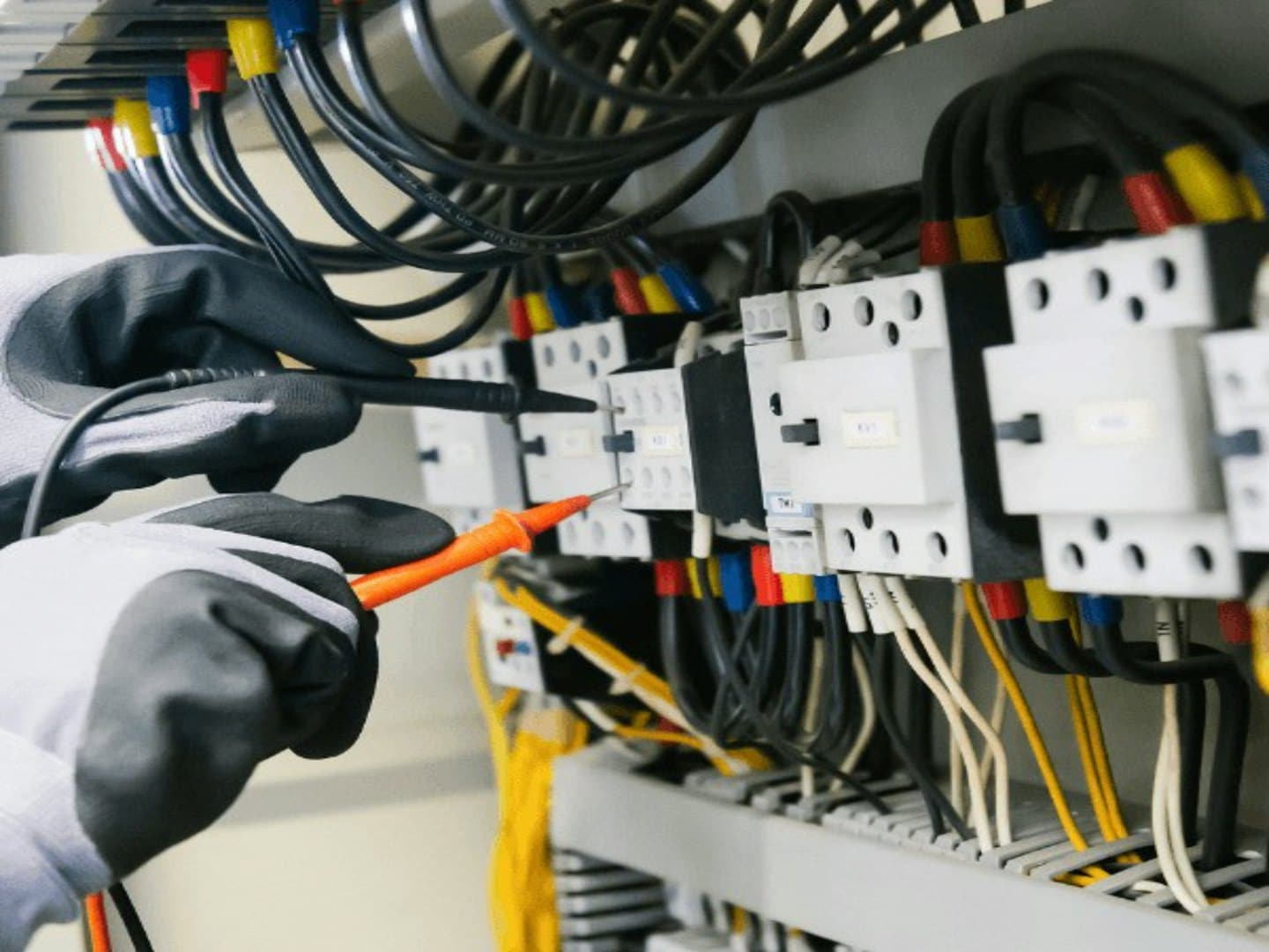 Rukavice technika testujú elektrický panel multimetrom.